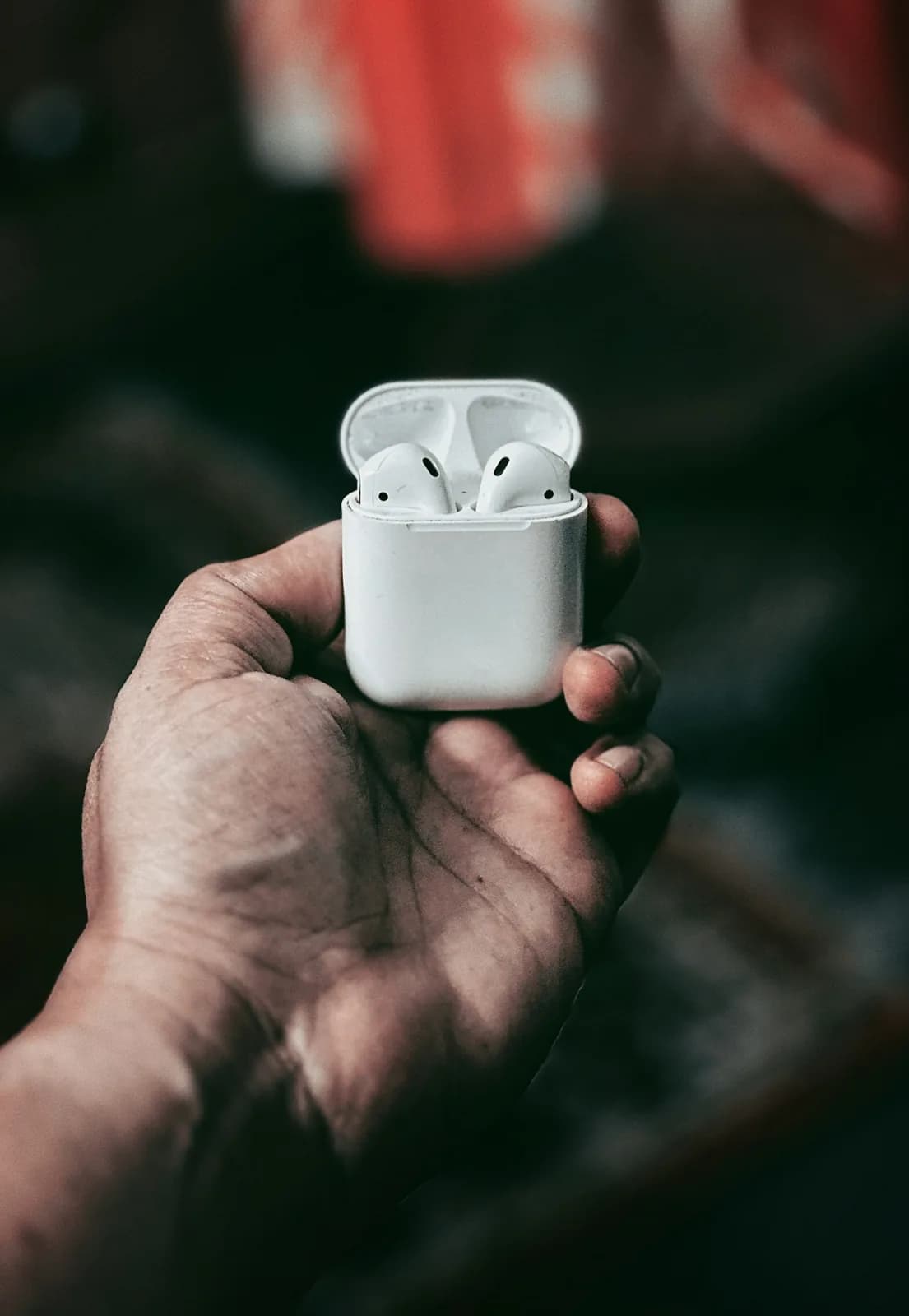 A hand holding an AirPods case
