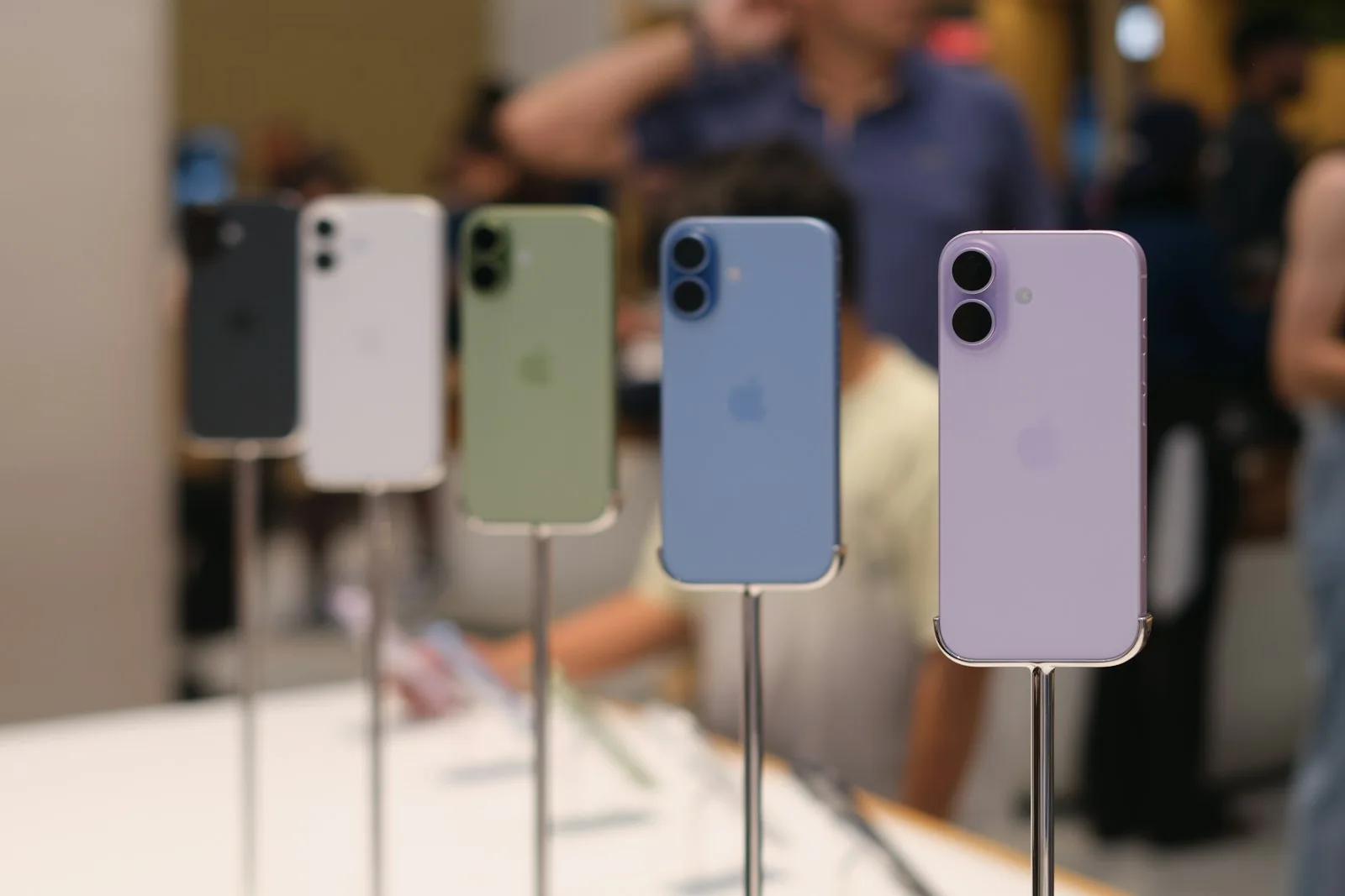 A row of iPhones in different colors standing on the counter