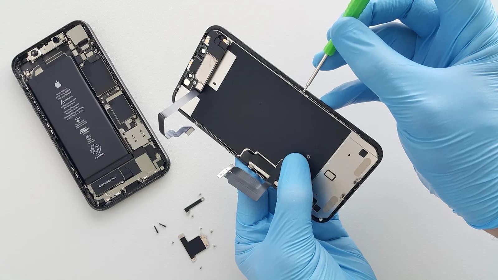 A technician in blue gloves replacing an iPhone screen