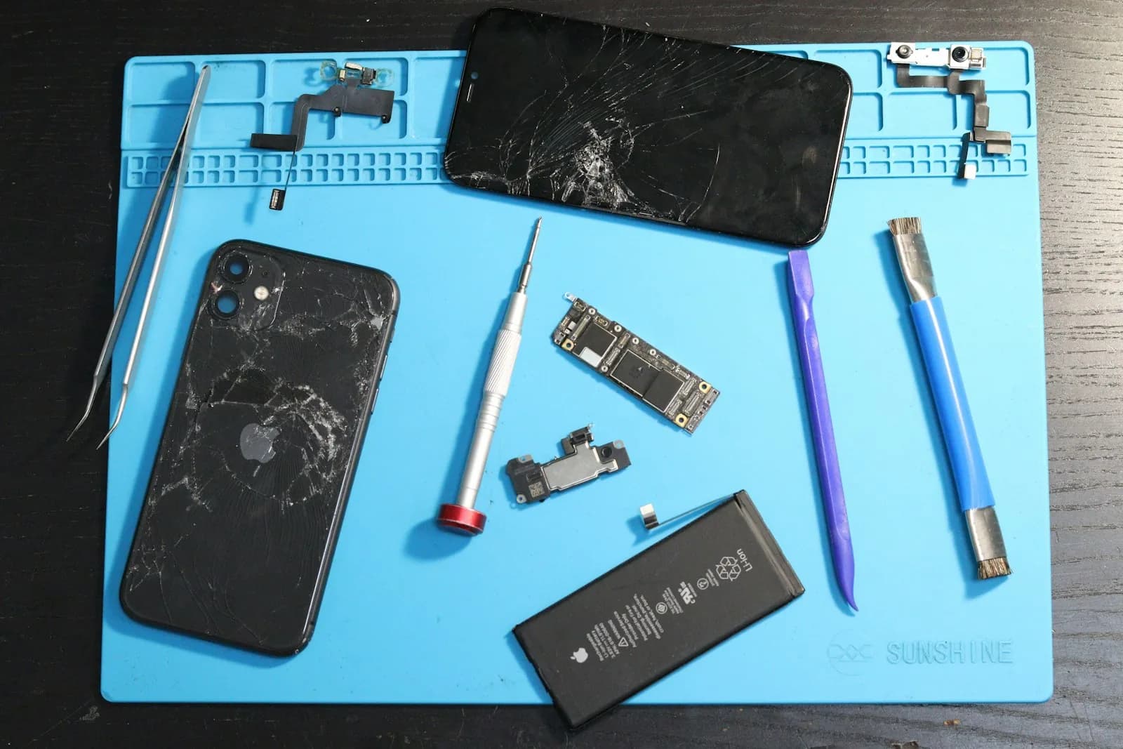 Cracked phone and repair tools on a work mat
